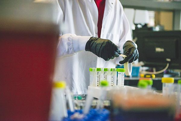 Lab student or employee adding tape to beakers in laboratory